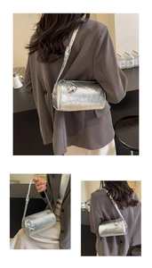 Detail of silver cylindrical pillow bag featuring metallic pleated texture and ball charm