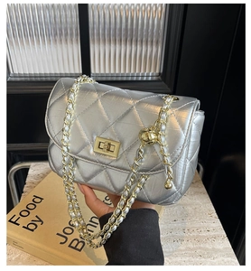 Detail of silver quilted chain bag with gold hardware and stylish metal adjustment ball