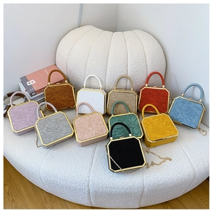 Detailed macro view of multi-colored embossed leather box bags with golden metal chain straps