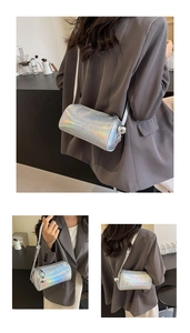 Detail showing holographic silver cylinder crossbody bag with metallic ball charm on model