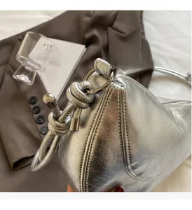 Detail of silver croissant bag with crinkled leather, metal ring, and knot design