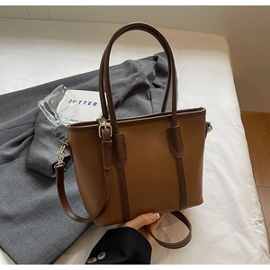 Détail d'un sac cabas bicolore marron avec boucles dorées et bandoulière réglable