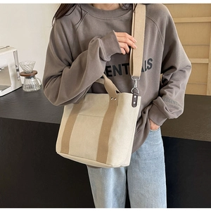 Modello che indossa una borsa in tela crema con cinturini marroni e tracolla regolabile