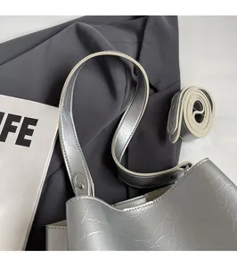 Détail du sac seau argenté montrant la surface texturée et les bretelles réglables