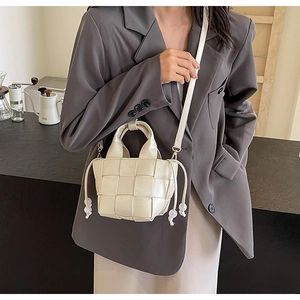 Détail du sac seau tressé crème avec poignée supérieure et cordon à perles