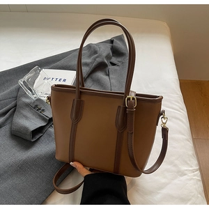 Détail d'un sac cabas bicolore marron avec boucles dorées et bandoulière amovible