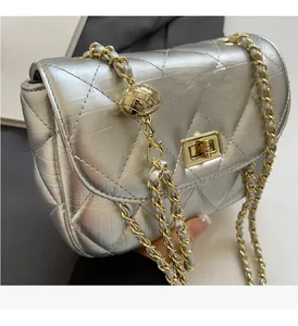 Detail of silver quilted chain bag featuring golden adjustable ball and metallic leather