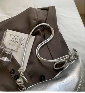 Detail of silver metallic croissant bag showing textured faux leather and knotted strap