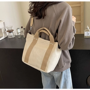 Dettaglio della borsa tote in tela con manici marroni e tracolla rimovibile nel caffè