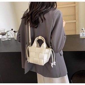 Détail de la texture tissée blanc crème et des perles du cordon du sac seau tendance