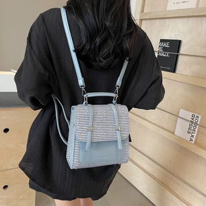 Minimalist light blue straw woven backpack with leather trim shown on model back
