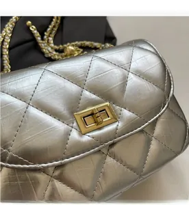 Close-up of silver quilted crossbody bag with gold turn-lock and pearl chain detail