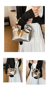 Detail of silver bucket bag with colorful beaded handle and metallic textured surface