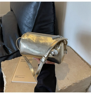 Detail of metallic gold pillow bag with crinkled texture and silver ball charm