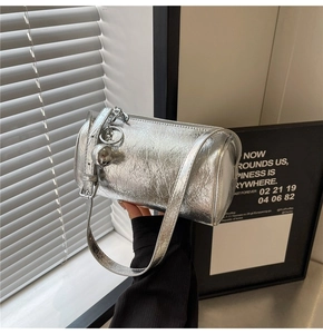 Detail of silver metallic barrel bag featuring pleated texture and spherical charm