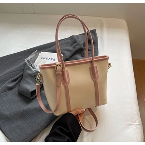 Détail d'un sac cabas bicolore en similicuir crème et rose avec boucles dorées
