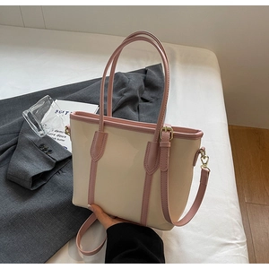 Détail d'un sac cabas crème chic avec bordure rose, finitions dorées et bandoulière amovible