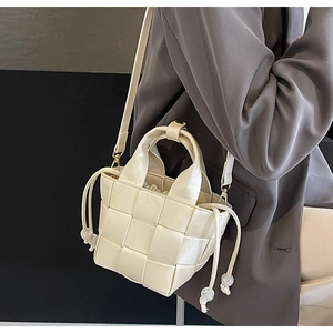 Détail d'un sac seau tressé crème avec fermeture à cordon et fine bandoulière réglable