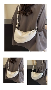 Detailed view of a white minimalist hobo bag featuring a unique knotted shoulder strap