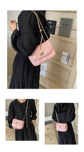 Detail of pink quilted crossbody bag with gold chain and adjustable ball on black dress