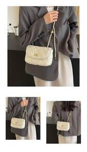 Detail of white quilted chain bag featuring golden ball adjustment and turn-lock closure