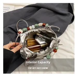 Silver metallic bucket bag with colorful beads showing internal capacity for cosmetics