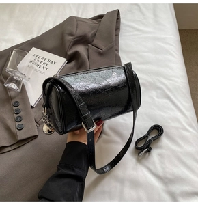 Macro shot of black glossy wrinkled leather pillow bag with silver zipper and extra strap