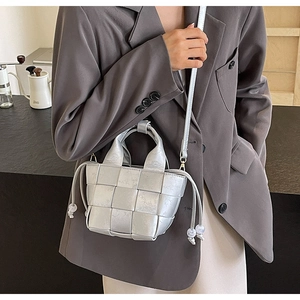 Mini sac seau tressé argenté avec cordon de serrage et bandoulière porté par un mannequin