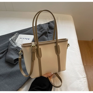 Gros plan du sac cabas bicolore beige et marron avec des détails en métal doré chic