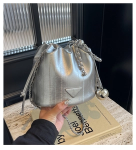 Detail showing the silver metallic drawstring bucket bag with textured finish and metal ball