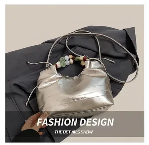 Close-up of silver bucket bag with resin beaded handle and logo brand engraving