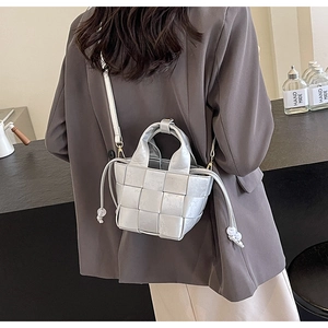 Détail du sac seau tressé argenté avec texture entrelacée et cordons à perles blanches