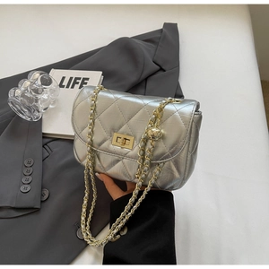 Detail of silver quilted mini bag with gold chain strap next to a grey blazer