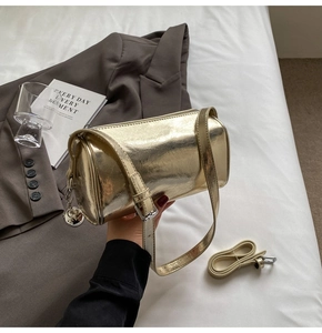 Detail of a golden cylinder pillow bag with pleated texture and silver ball charm
