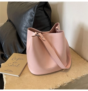 Détail du sac seau rose clair avec motif litchi, anneaux argentés et texte mode