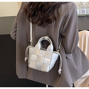 Sac seau tissé argenté en cuir porté par un mannequin pour un look de rue contemporain