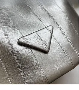 Macro detail of silver pleated bucket bag featuring metallic logo and textured finish