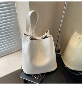 Détail du sac seau crème montrant la texture grainée et le lettrage minimaliste