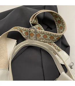 Details des geometrischen Jacquard-Gurtes und des weißen Ledergriffs mit Krokoprägung