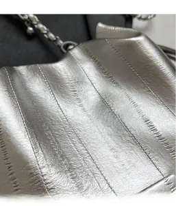 Detail of silver metallic textured fabric with vertical stitching and chain strap