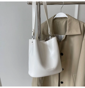 Gros plan d'un sac seau blanc montrant la texture cuir craquelé vintage et le logo