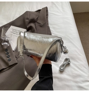 Detail of silver metallic cylinder bag with wrinkled leather texture and sphere charm