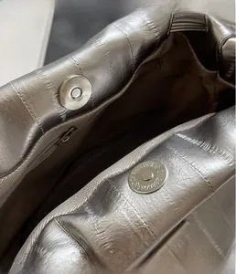 Detailed close-up of silver pleated bag featuring dual magnetic buckles and inner zipper pocket