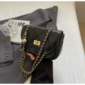 Detail of black quilted leather mini bag with gold chain strap and ball charm