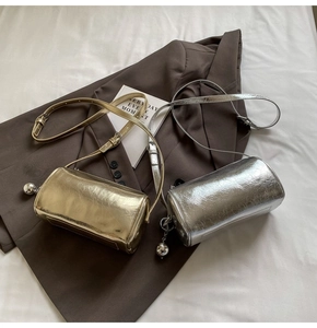 Detail of metallic pleated cylinder bags in gold and silver with adjustable straps