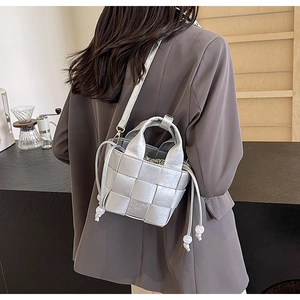Détail du sac seau tressé argenté avec imprimé floral et bandoulière réglable