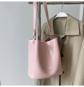 Détail d'un sac seau rose en cuir gaufré suspendu à un support métallique élégant