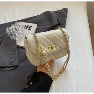 Close-up of quilted cream chain bag with gold twist lock and adjustable metal ball