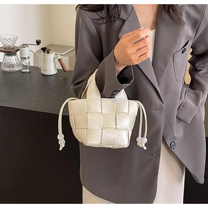 Détail du sac seau tissé crème avec perles de serrage et texture à larges carreaux