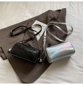 Detail of cylinder crossbody bags in black pleated leather and holographic silver finish